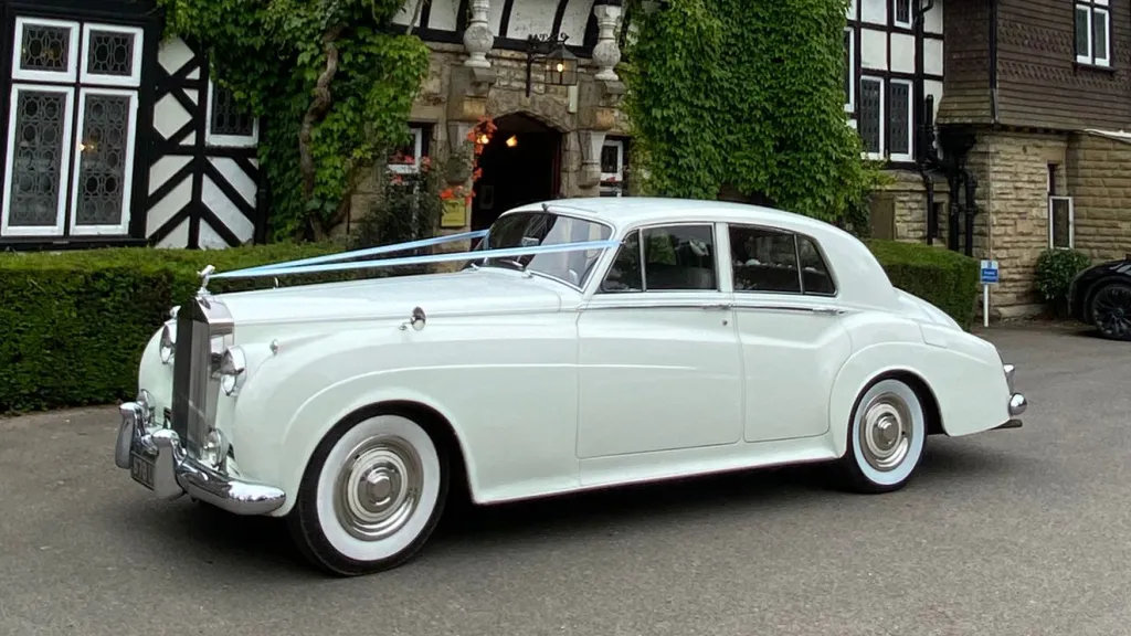 White Rolls-Royce Silver Cloud with classic whitewall tyres parked on gravel