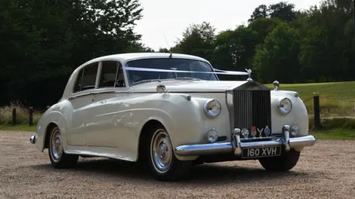 Cream Classic Rolls-Royce Silver Cloud dressed with white wedding ribbons