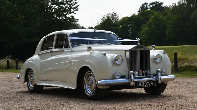 Cream Classic Rolls-Royce Silver Cloud dressed with white wedding ribbons
