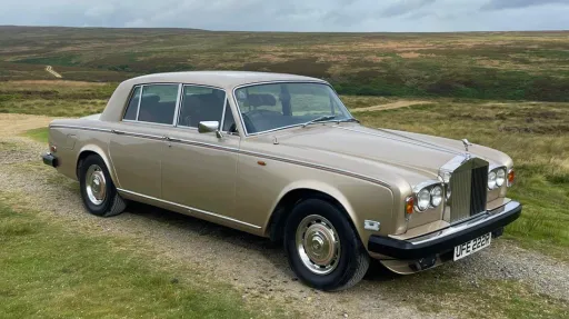 Side profile view of a gold Rolls-Royce Silver Shadow on open moorland, available for weddings in Yorkshire.