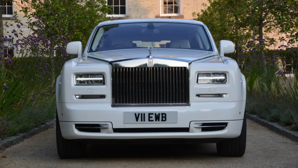 full front view of White rolls-royce phantom with tall chrome front grill at the entrance of Froyle Park.