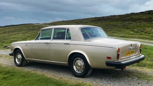 Left rear angle view of a gold Rolls-Royce Silver Shadow parked on countryside road, available for wedding hire in Yorkshire.