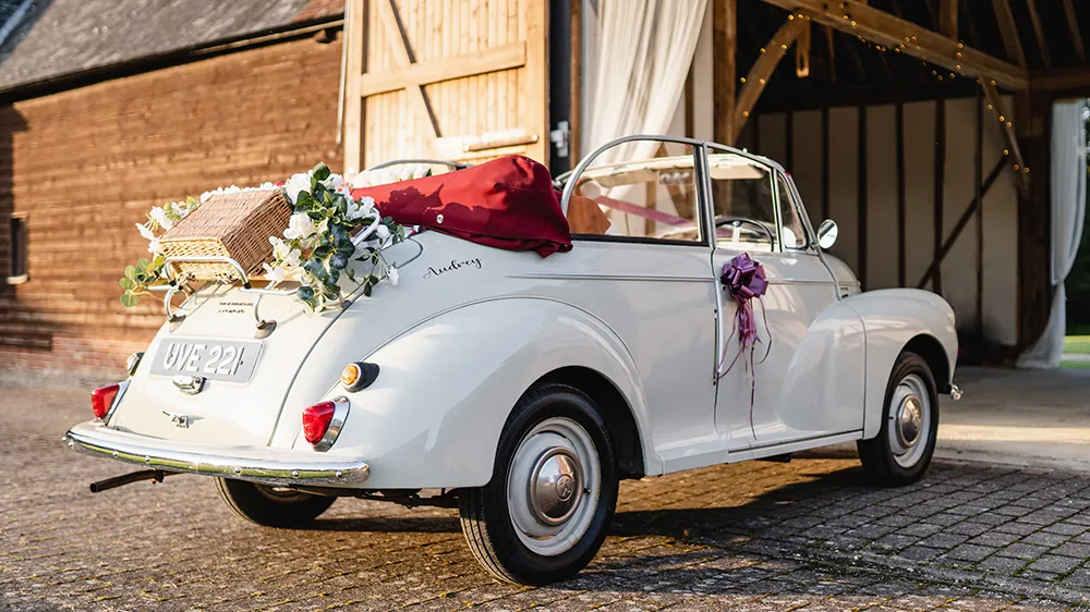 Rear right view of classic Morris Minor Convertible with opened up soft top roof and chrome bumper and flower decoration