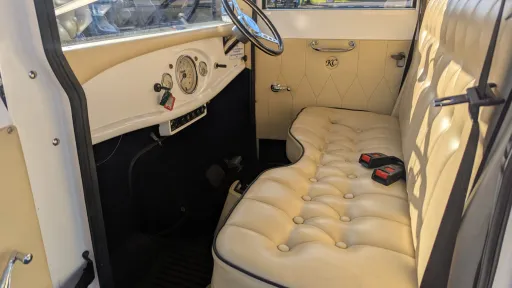 Front seat and driver’s cabin inside an Imperial vintage wedding bus with cream leather upholstery and polished details.