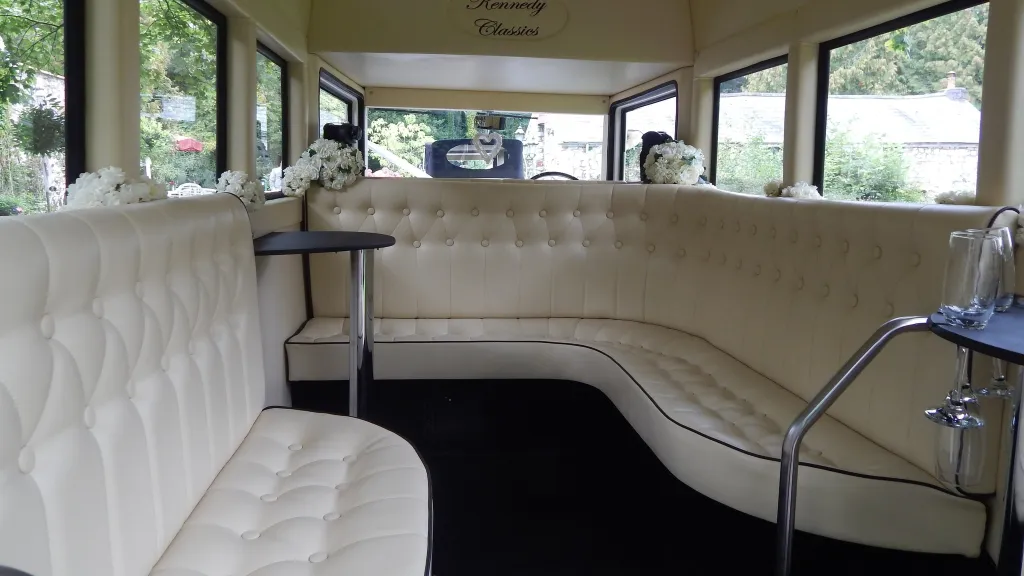 Cream leather wraparound seating inside an Imperial vintage wedding bus with windows all around letting in natural light.