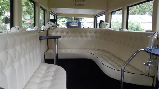 Cream leather wraparound seating inside an Imperial vintage wedding bus with windows all around letting in natural light.