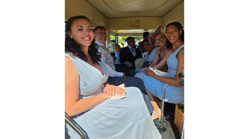 Wedding party seated inside an Imperial vintage wedding bus, smiling and dressed in formal attire with cream interior seating.