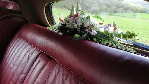 Rear parcel shelf inside a 1954 Rolls-Royce Silver Dawn, decorated with a floral wedding arrangement beneath the rear window.