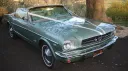 Front view of a classic Ford Mustang convertible decorated with white wedding ribbons tied across the bonnet.