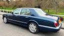 Left rear side view of a Windsor Blue Bentley Arnage with chrome details, parked on a country lane.