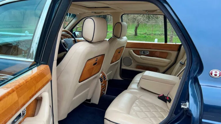 View of the Bentley Arnage’s cream leather rear seats from the right-hand side with walnut wood finishes.