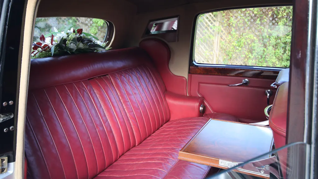 Luxurious red leather seating inside the 1954 Rolls-Royce Silver Dawn, featuring classic wood veneer trim and spacious rear cabin.