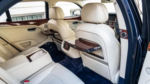 Rear interior seating area with cream leather seats, wooden picnic table open and royal blue carpet