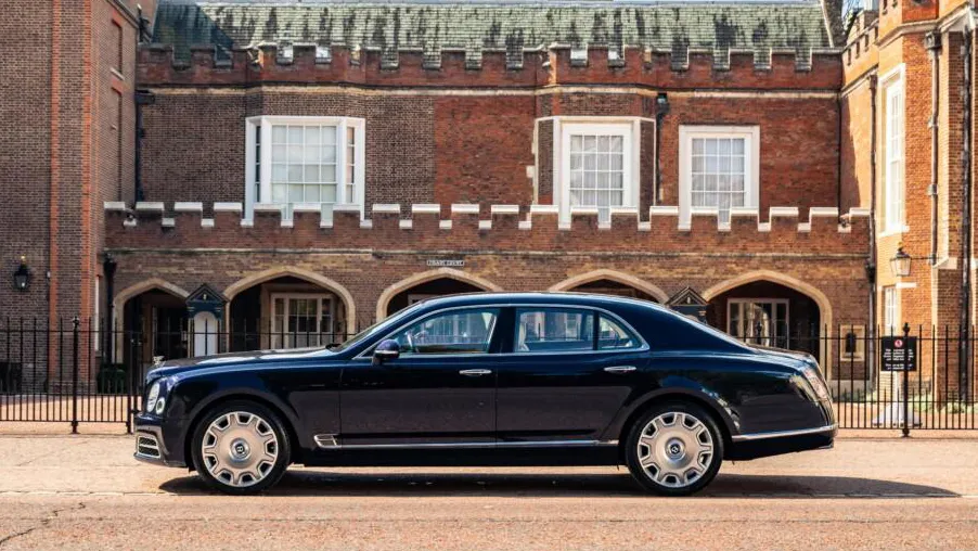 Left sode view Blue Bentley Mulsanne parked in front of a red brick wedding venue