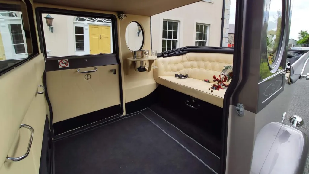 Interior of a silver Imperial wedding car featuring cream leather seating, wooden trim, and a spacious rear cabin.