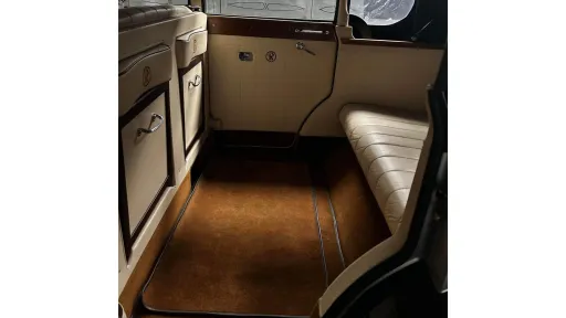 Rear seating area of a Regent wedding car featuring cream leather seats and wood-panel details with fold-down occasional seats.