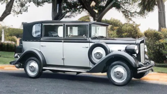 Right side profile of a silver and black Regent Landaulette wedding car with white ribbons and classic chrome details, parked on grass.