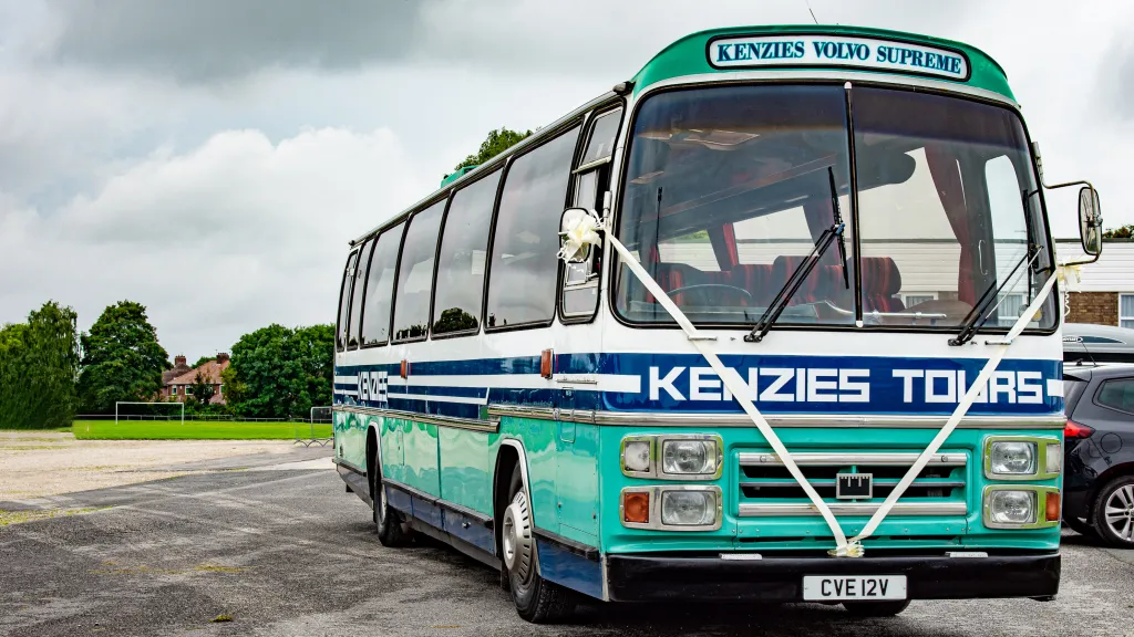 Vintage turquoise single-decker bus decorated for a wedding, photographed on a quiet road surrounded by greenery in Yorkshire.