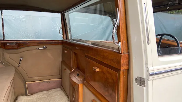 Interior of a 1948 Rolls-Royce Silver Wraith featuring polished wooden trim, tan leather upholstery, and large spcious rear seating for passengers.