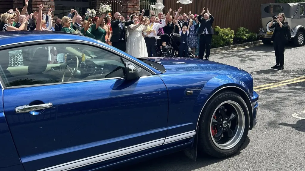 Close-up of a modern blue Ford Mustang showing its sharp styling, bonnet vents, and racing stripes.