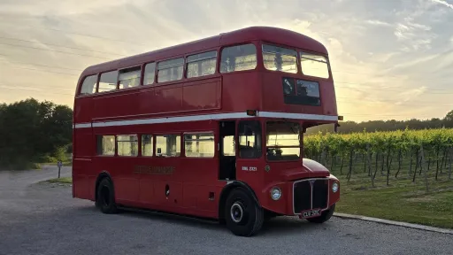 Vintage red Routemaster double-decker bus parked at dusk with warm evening light reflecting off its classic bodywork.