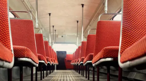 Interior of a vintage Routemaster double-decker bus showing red seats, cream ceilings, and traditional lighting.
