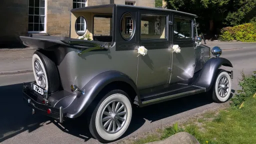 Silver Imperial convertible vintage-style wedding car parked on a sunny lane in Sussex, with the roof down and decorated for a wedding.