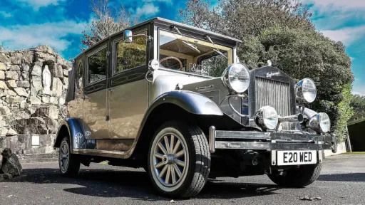 Two-tone silver Imperial vintage wedding car with chrome headlights and sweeping wings parked under a bright blue sky in Antrim.