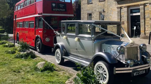Silver Imperial vintage wedding car parked beside a classic red Routemaster double-decker bus at a Sussex wedding venue.