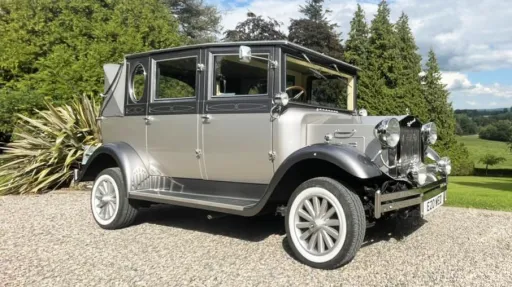 Classic silver Imperial vintage wedding car parked beside landscaped gardens in Northern Ireland.