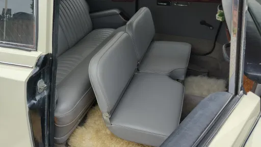 Interior view of a Daimler DS420 limousine showing its additional fold-down seats and grey leather upholstery.