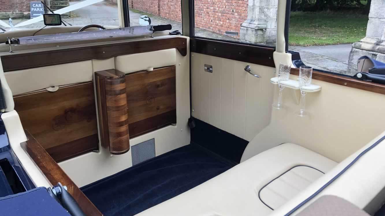 Rear seating area of the Regent vintage wedding car with cream leather upholstery and decorative wooden trim.