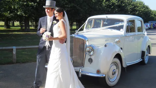 Bride and Groom standing in front of a white Bentley