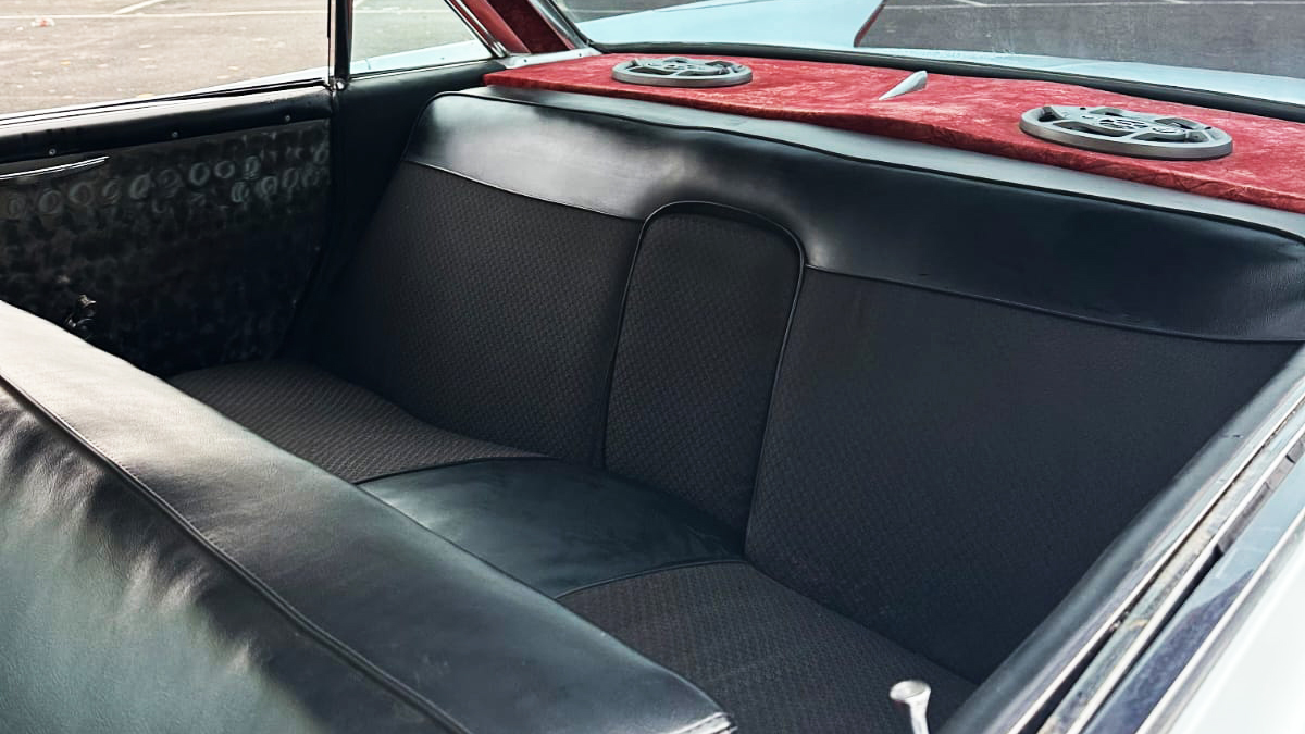 Rear black bench seat inside a classic white Cadillac wedding car.