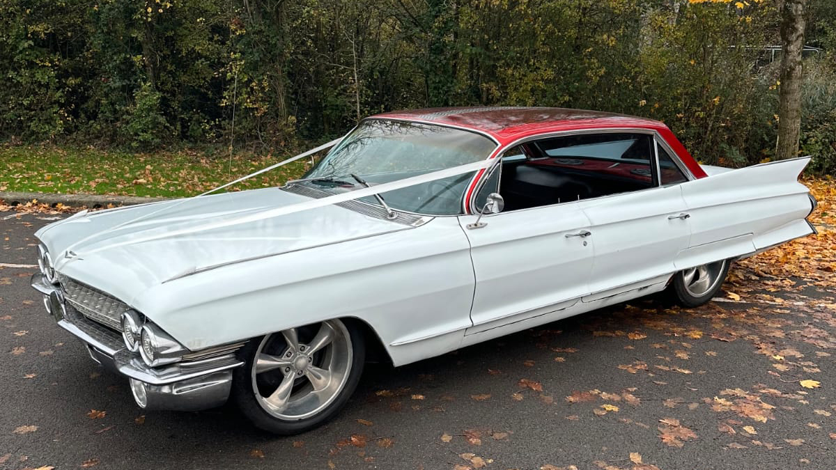 White classic American Cadillac with red roof parked outdoors.