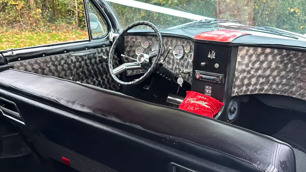Driver’s seat and steering wheel inside a classic Cadillac with retro controls.