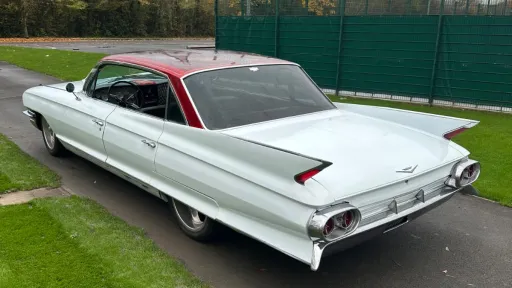 Left side exterior view of a white vintage Cadillac with red roof.