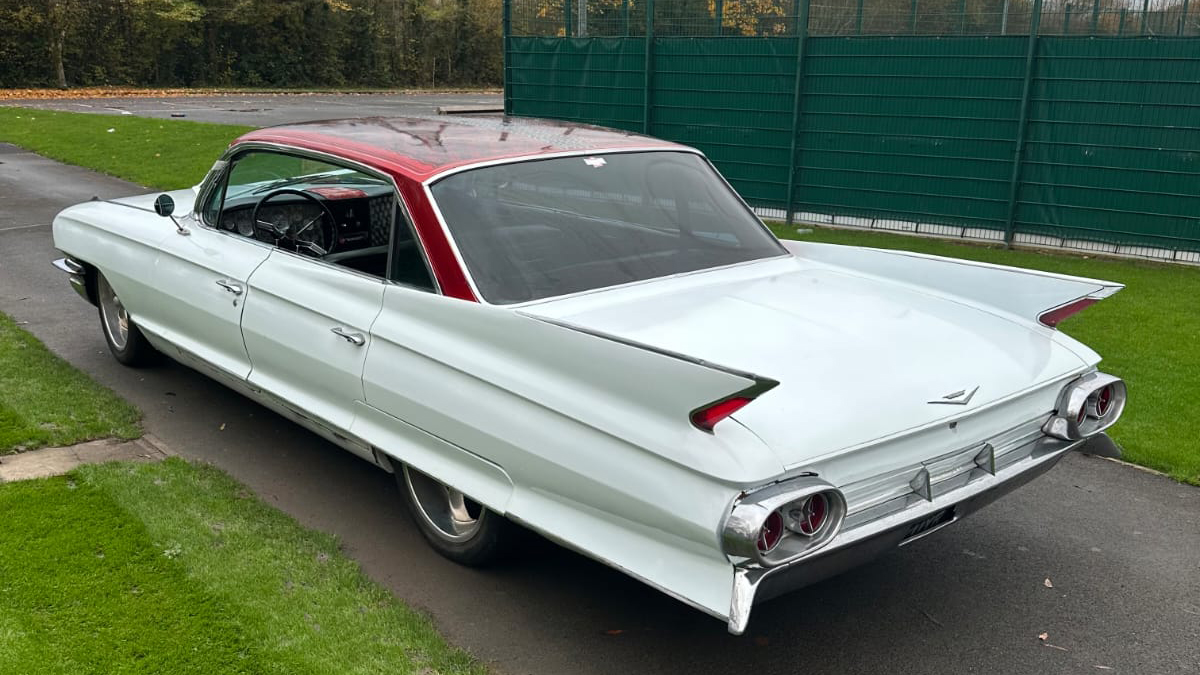 Left side exterior view of a white vintage Cadillac with red roof.