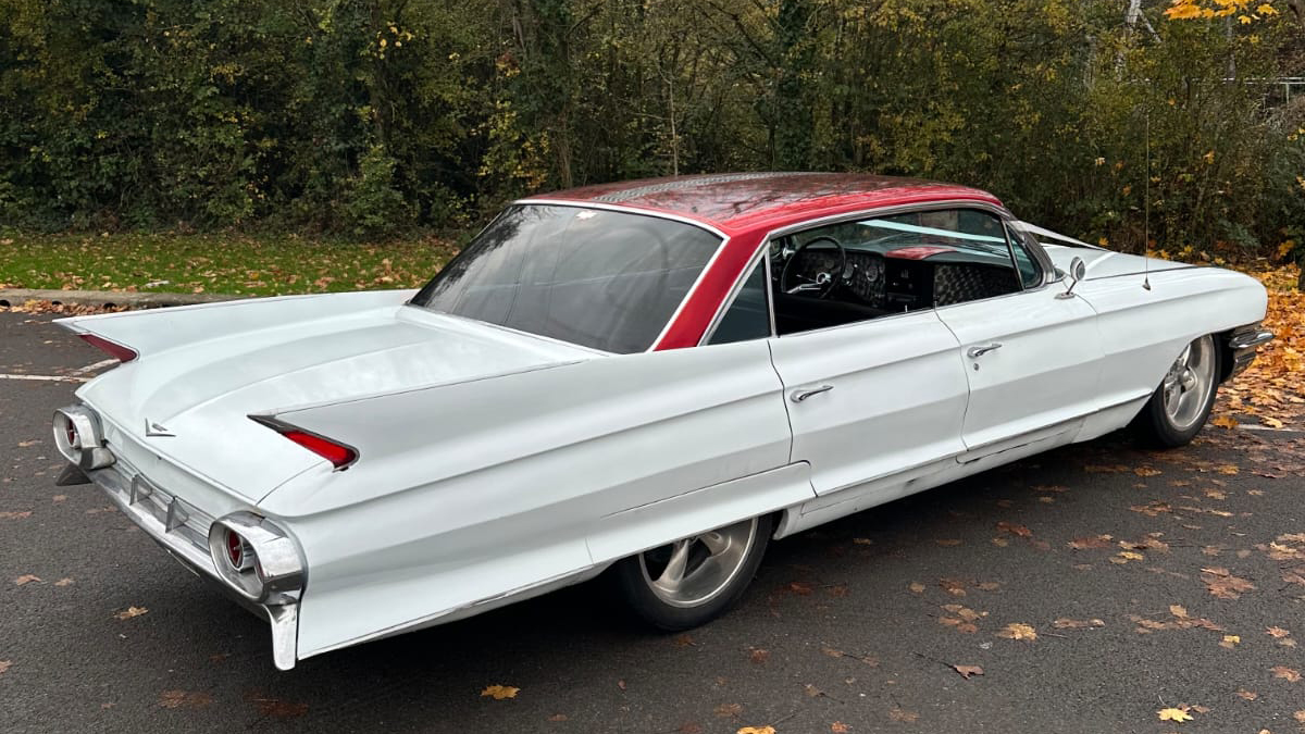 Right side exterior view of a white classic American Cadillac parked on driveway.