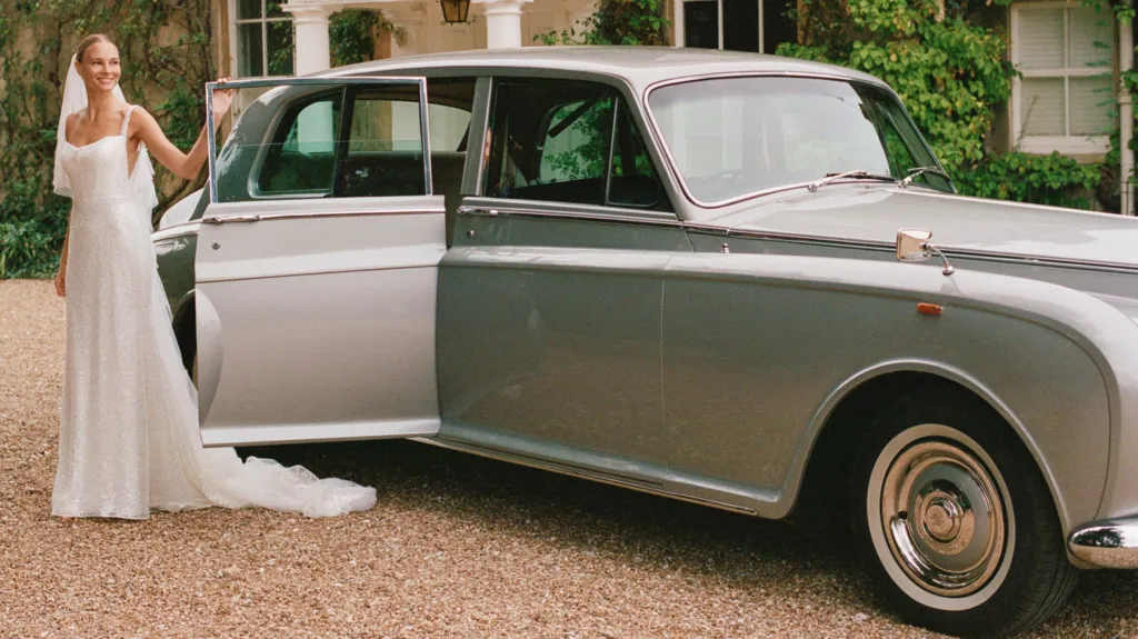 Bride standing beside a classic Rolls-Royce Phantom limousine with her white gown flowing.