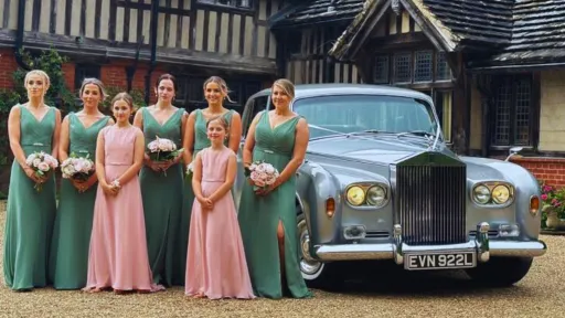 Bridesmaids and flower girls standing beside a classic Rolls-Royce Phantom wedding car.