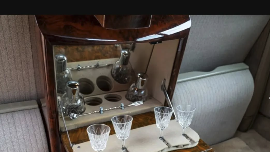 Polished wooden drinks cabinet inside a vintage Rolls-Royce Phantom limousine.