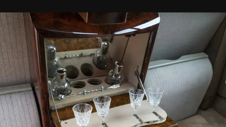 Polished wooden drinks cabinet inside a vintage Rolls-Royce Phantom limousine.