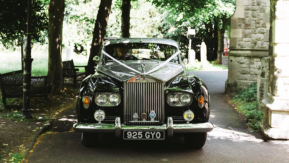 front view of Rolls-Royce Silver Cloud with twin headlamps outside country house and decorated with wedding ribbons