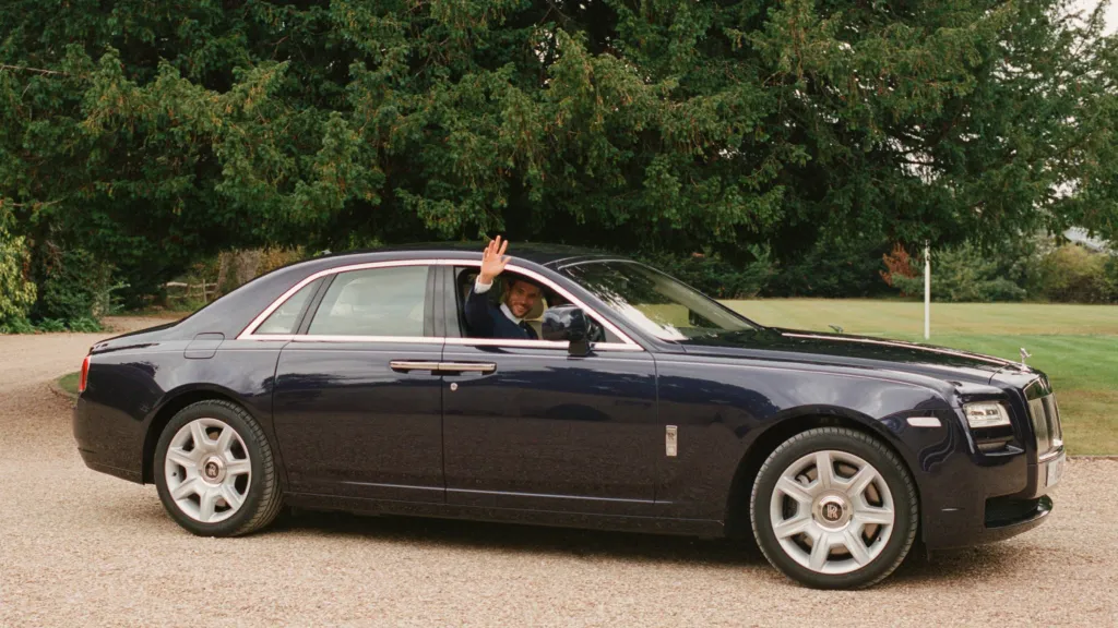 right side view of Rolls-Royce Ghost driving with groom waving