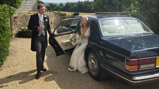 bride exiting Rolls-Royce Silver Spirit with groom assisting