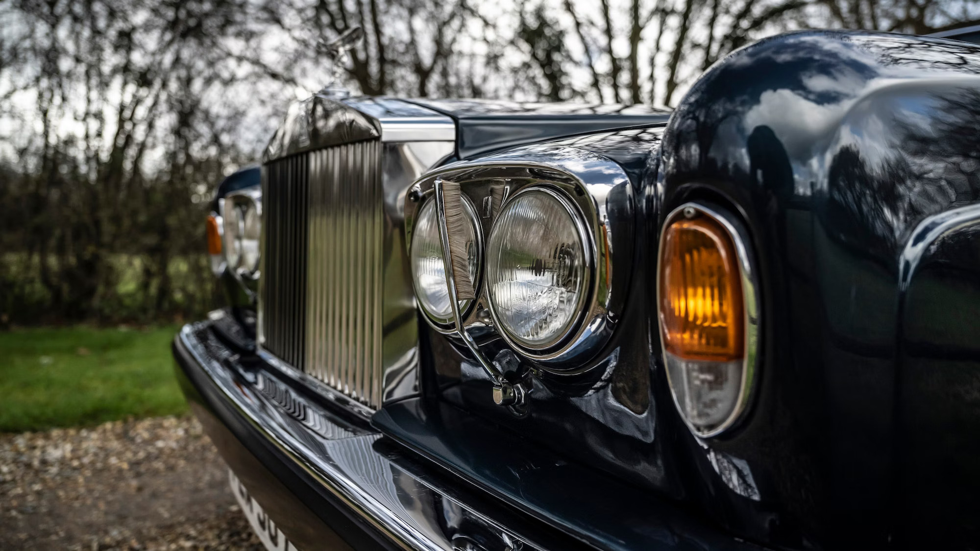 close up view of twin headlights and large chrome grill of a Rolls-Royce Corniche.