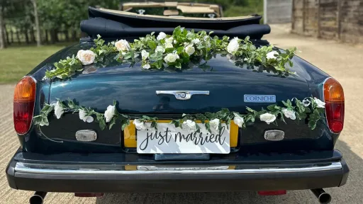 Floral decoration and Just Married sign on the rear boot of a blue Rolls-Royce Corniche