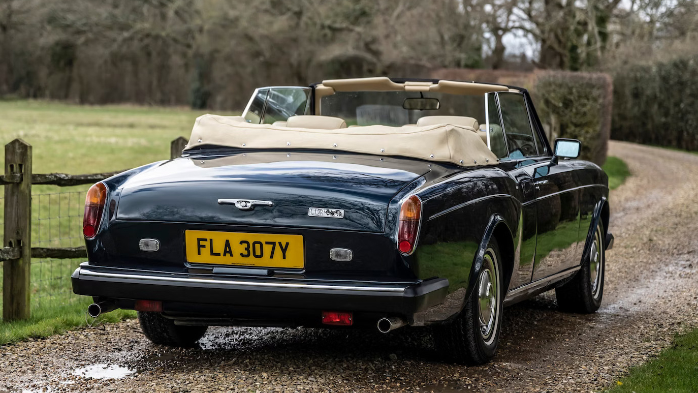 Rear view classic rolls-royce with convertible roof open showing cream leather interior