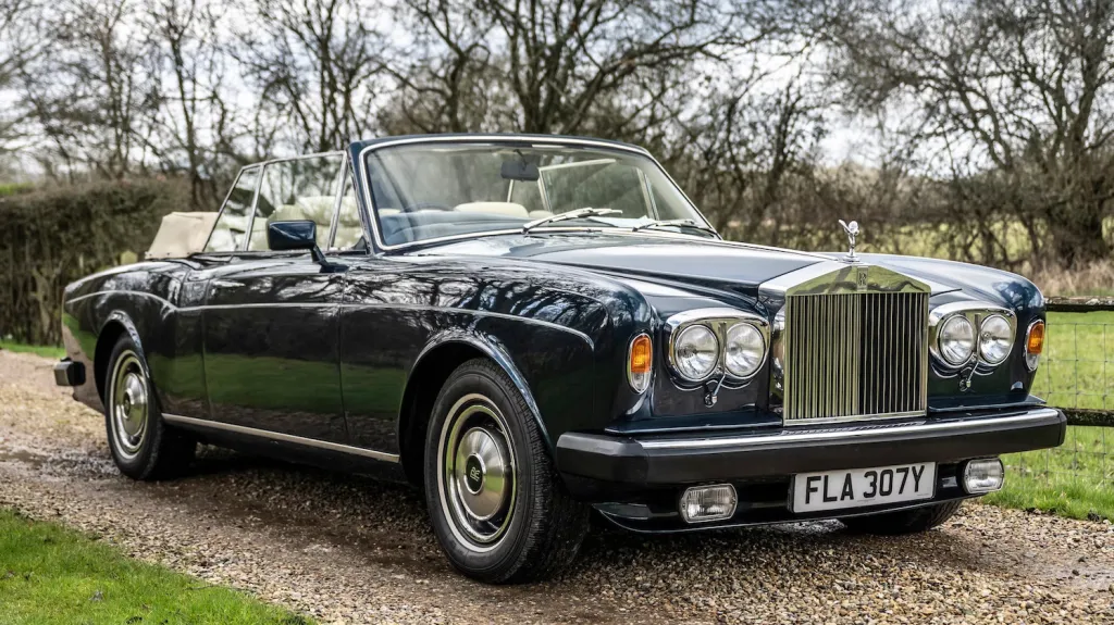 Right front view of blue Rolls-Royce corniche with twin headlights and soft top roof open